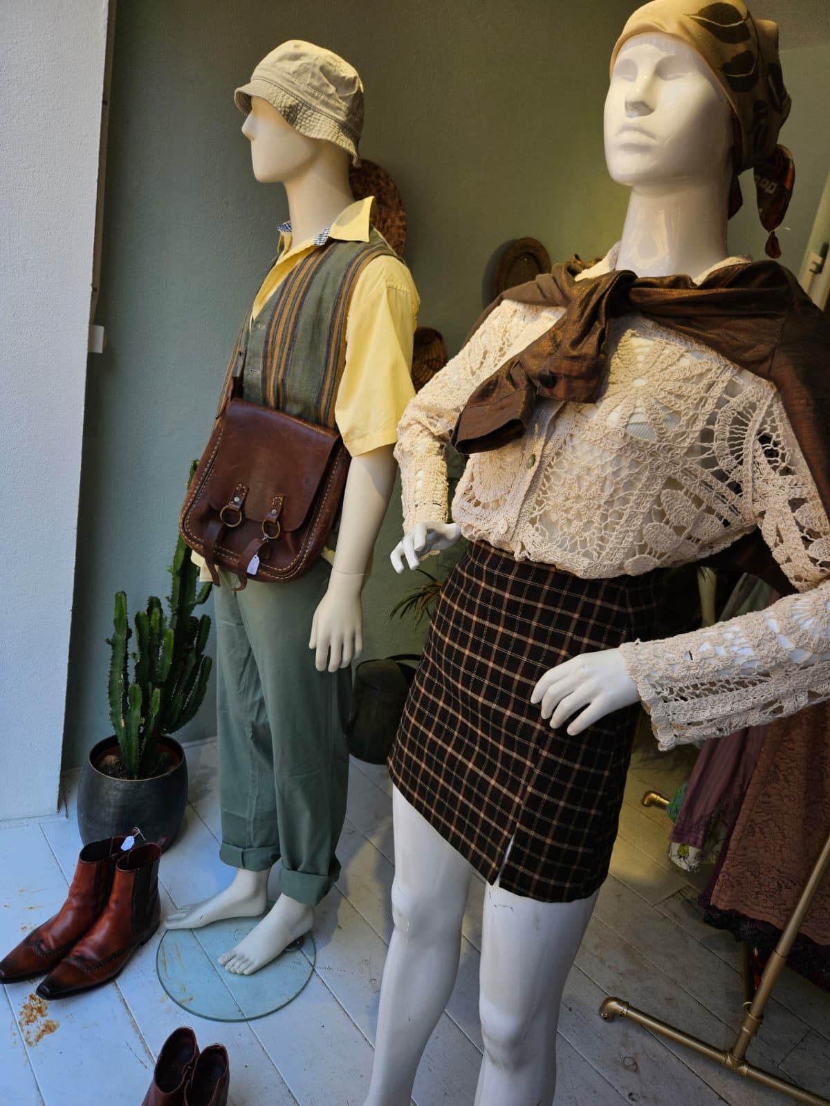 Twee etalagepoppen in de winkel · een heren-outfit met gilet en een dames-outfit met kanten blouse en ruit-rok.